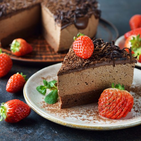 Chocolate cake decorated with strawberries on a brown background
